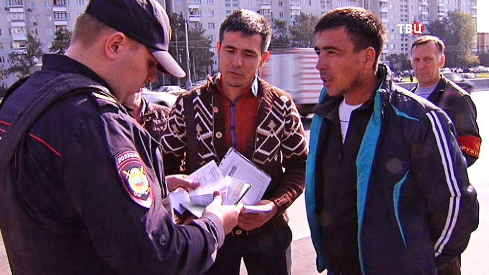 Полицейский проверяет документы у мигрантов Полицейский проверяет документы у мигрантов