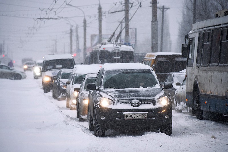 Автомобили во время сильного снегопада на одной из улиц города Омска