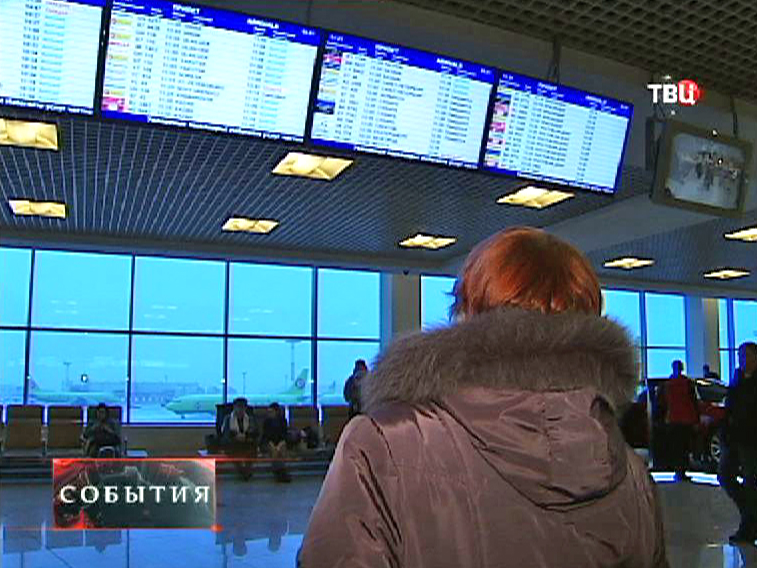 Женщина смотрит расписание авиарейсов на табло Женщина смотрит расписание авиарейсов на табло
