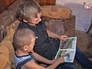 Подросток читают книгу своему брату Подросток читают книгу своему брату