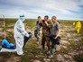 Специалисты в костюмах биозащиты работают с населением на месте заражения Специалисты в костюмах биозащиты работают с населением на месте заражения