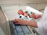 Врачи обследуют новорожденного ребенка Врачи обследуют новорожденного ребенка