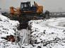 Бульдозер засыпает траншею с трубами для отвода газа при дегазации в ходе рекультивации полигона твердых бытовых отходов "Кучино" Бульдозер засыпает траншею с трубами для отвода газа при дегазации в ходе рекультивации полигона твердых бытовых отходов "Кучино"