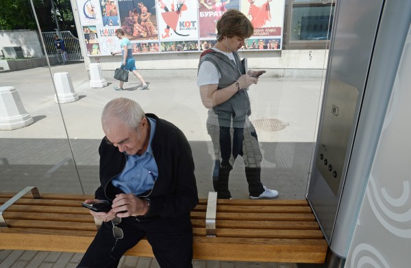 Пассажиры со смартфонами на остановке общественного транспорта
