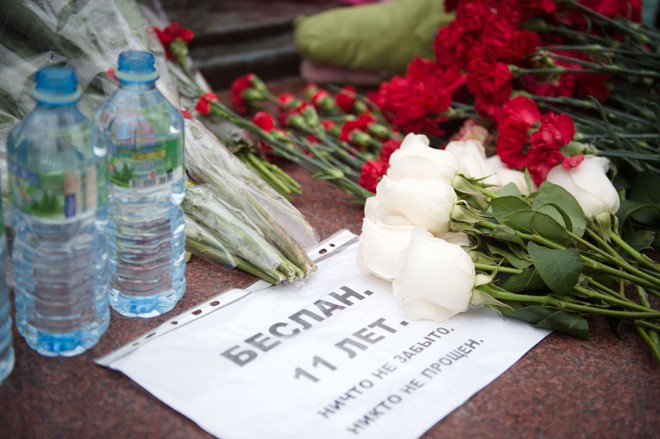 Люди возлагают цветы к памятнику жертвам трагедии в Беслане