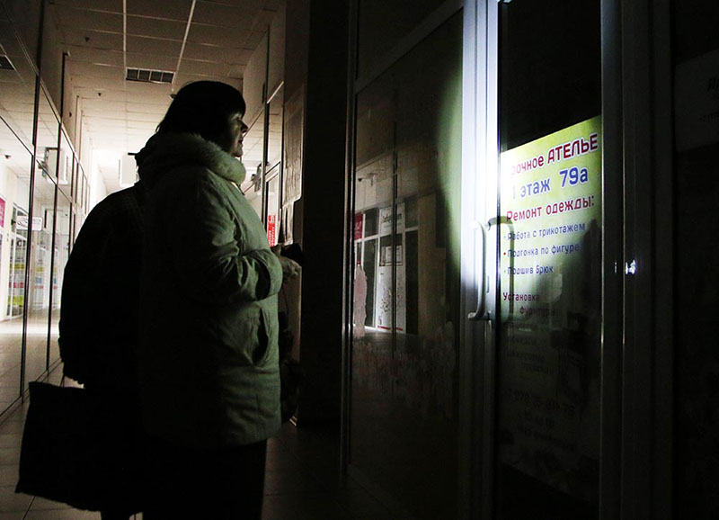 Женщина у закрытого, из-за отсутствия электричества, ателье по ремонту одежды в Симферополе