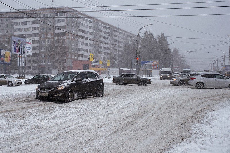 Автомобили во время сильного снегопада на одной из улиц города Омска