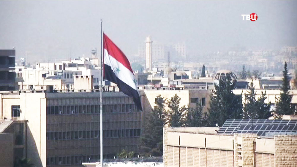 Флаг Сирии на фоне города
