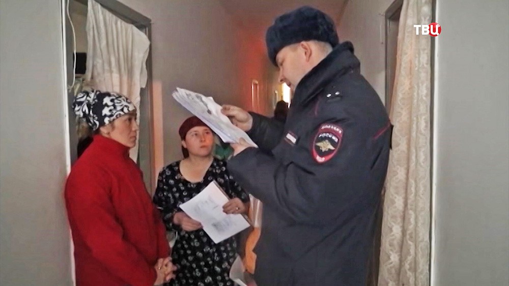 Сотрудник полиции проверяет документы у мигрантов 