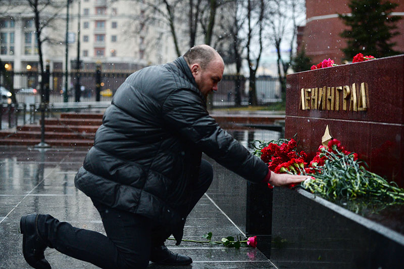 Мужчина возлагает цветы к мемориалу города Ленинград