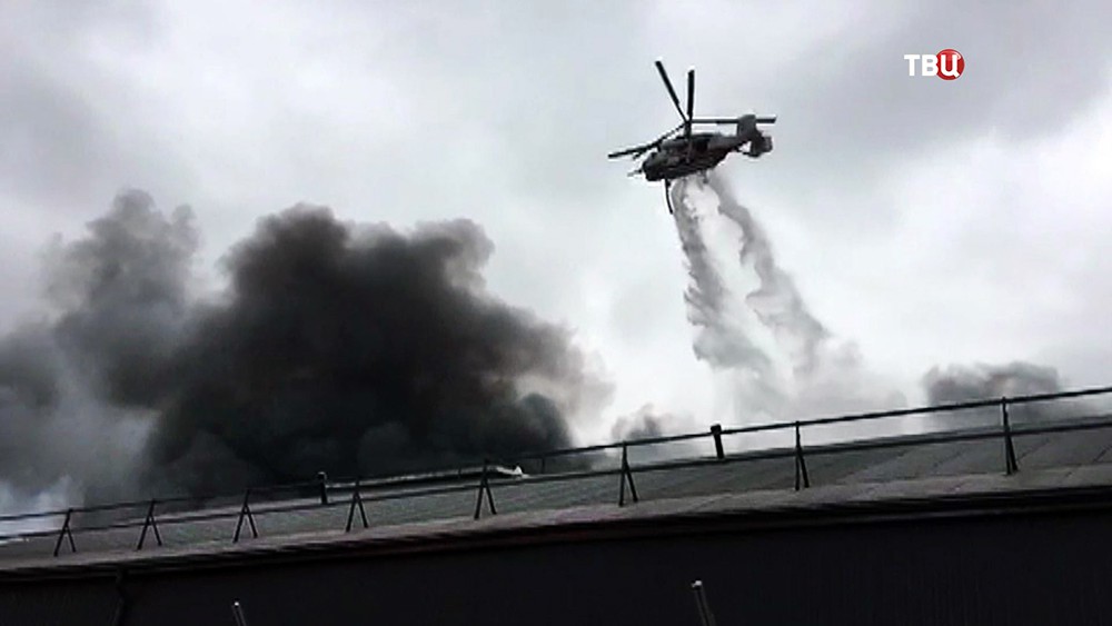 Пожарный вертолет сбрасывает воду на место возгорания в промзоне
