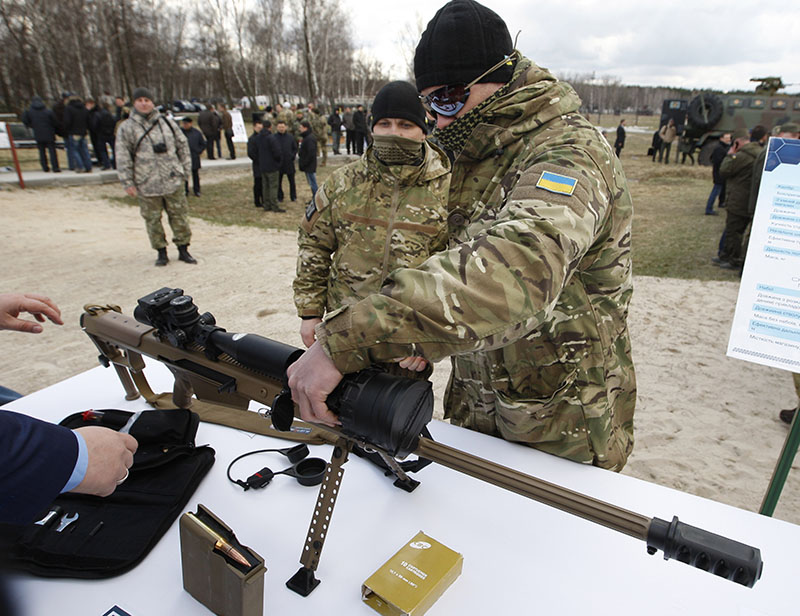 Украинский военный осматривает снайперскую винтовку 