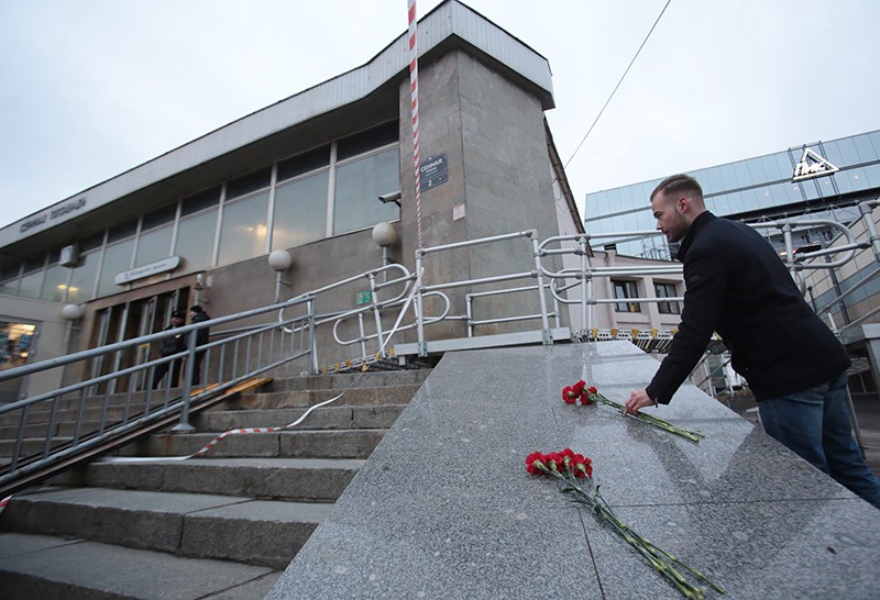 Мужчина возлагает цветы у входа в вестибюль станции метро "Сенная площадь" в память о погибших в результате взрыва в метрополитене Санкт-Петербурга