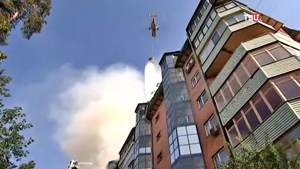 Пожарный вертолет работает на месте возгорания в многоэтажном доме