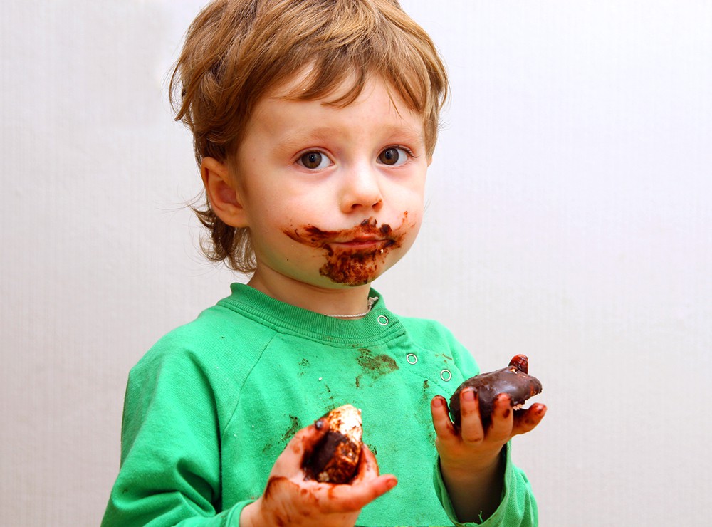 Ребенок ест зефир в шоколаде