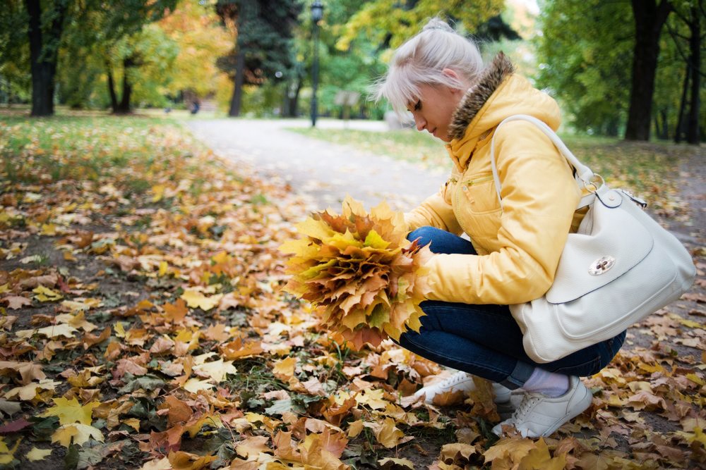 Девушка собирает осенние листья