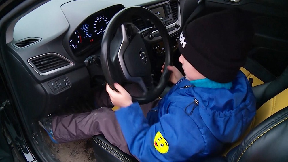 6-летний мальчик сидит за рулём машины