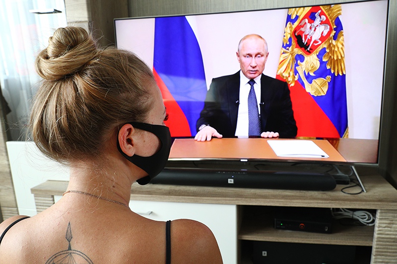 Девушка смотрит обращение Владимира Путина по телевизору