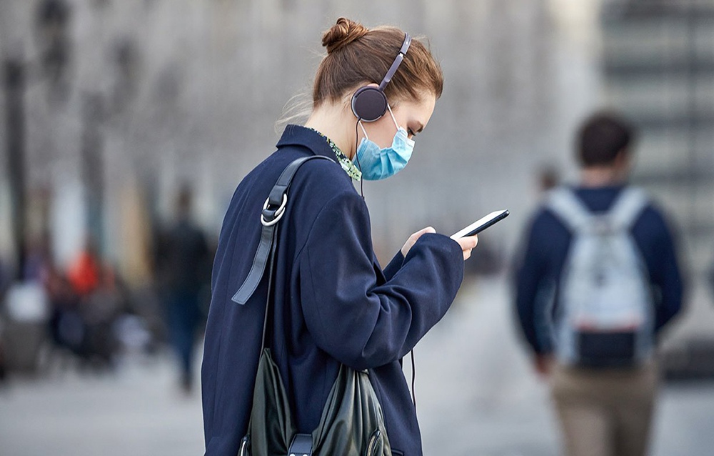 Девушка в медицинской маске и со смартфоном