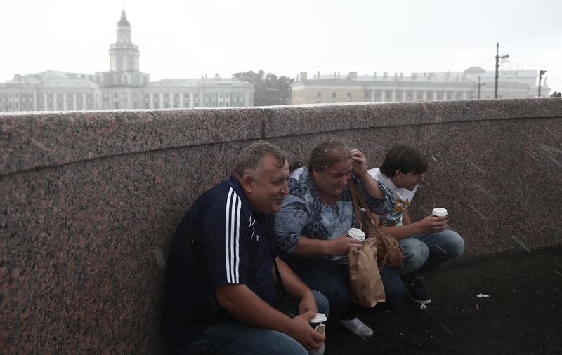 Жители Санкт-Петербурга на одной из улиц города во время сильного дождя