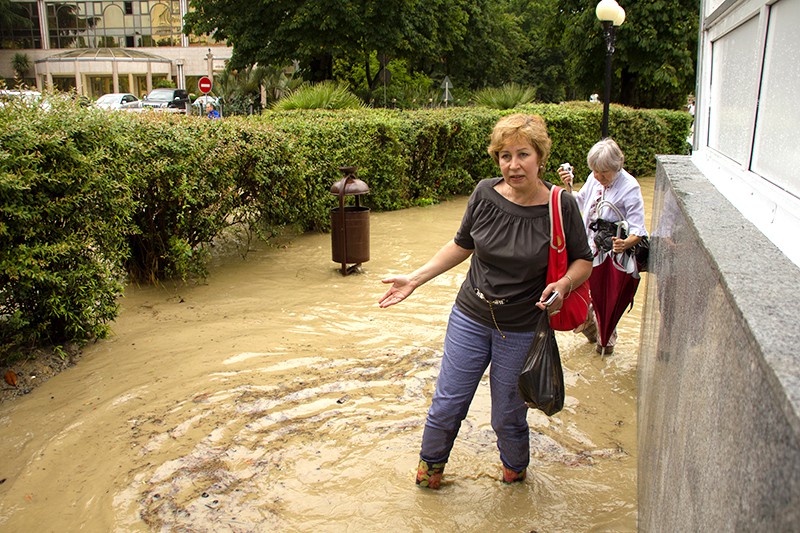 Жители идут по улице Сочи после проливного дождя
