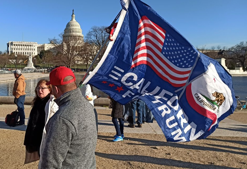 Мужчина с флагом сторонников Дональда Трампа на Капитолийском холме в Вашингтоне