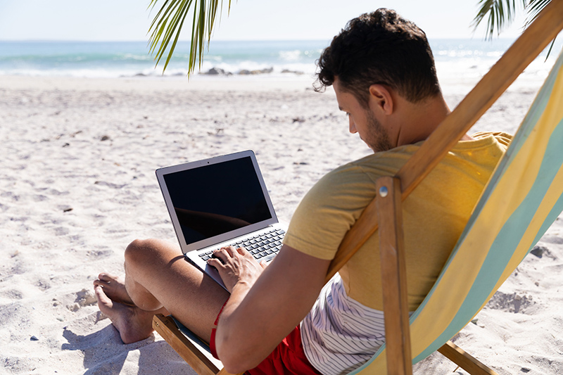 Мужчина с ноутбуком на пляжеся 