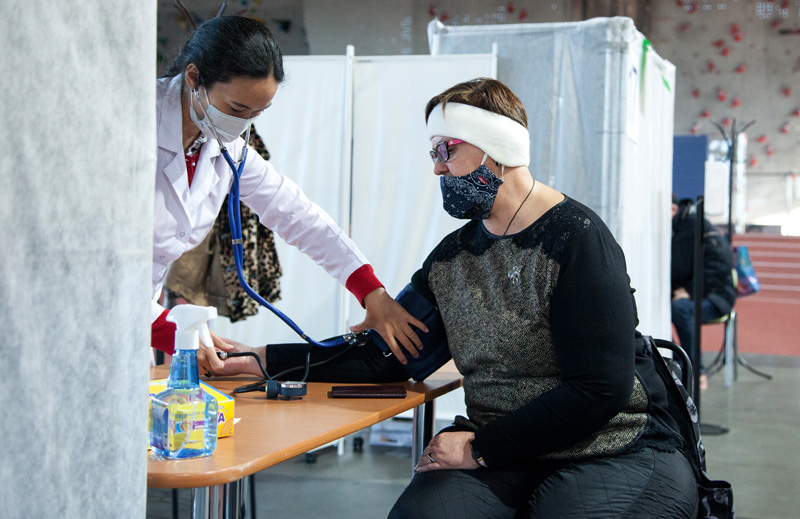 Медицинский сотрудник измеряет давление женщине перед вакцинацией в центре вакцинации от COVID-19