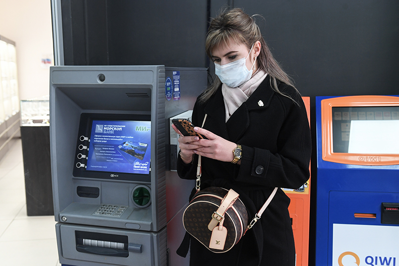 Девушка стоит возле банкомата